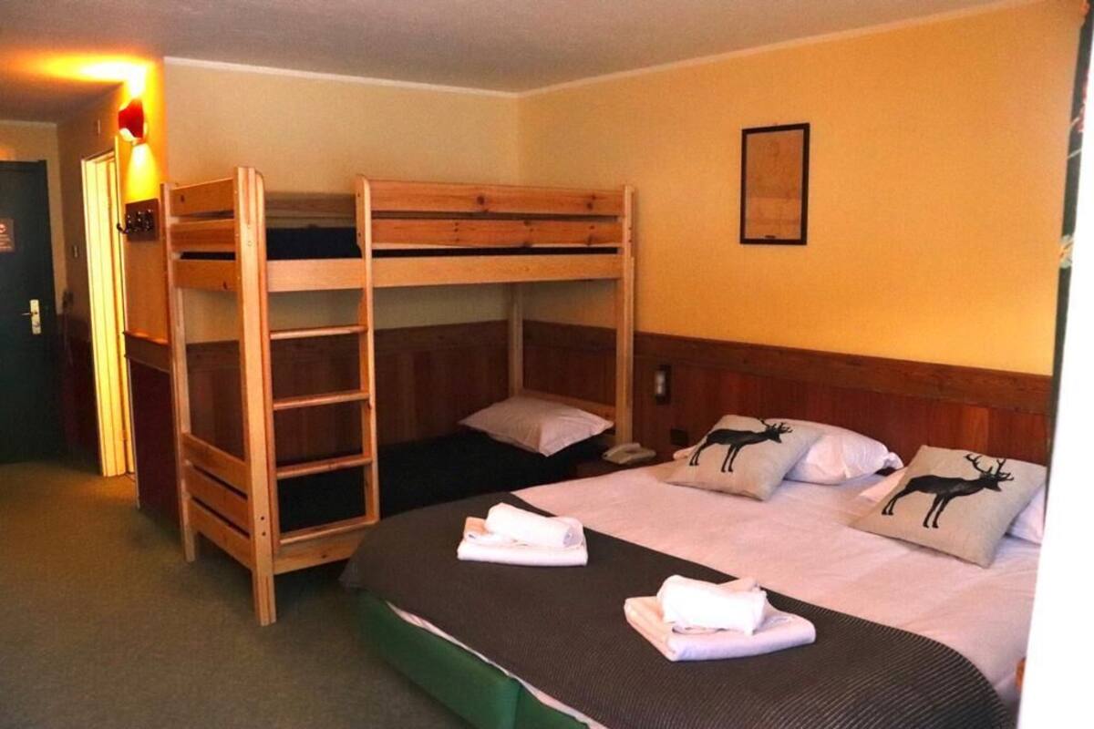 A room with bunk beds, a bedside table, a lamp, and a framed picture on the wall.