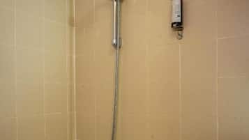 A bathroom with a bathtub, a showerhead, and a handrail.