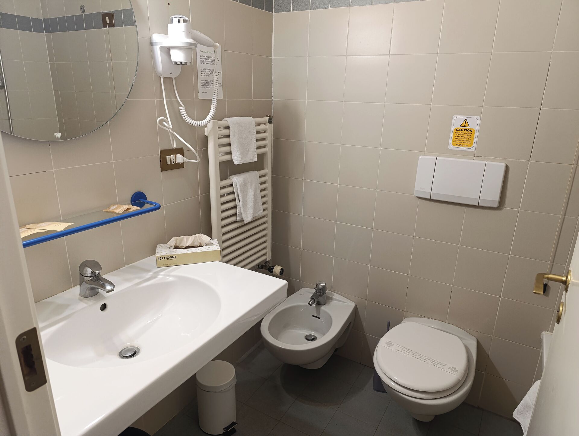 A bathroom with a sink, bidet, toilet, and a towel rack.