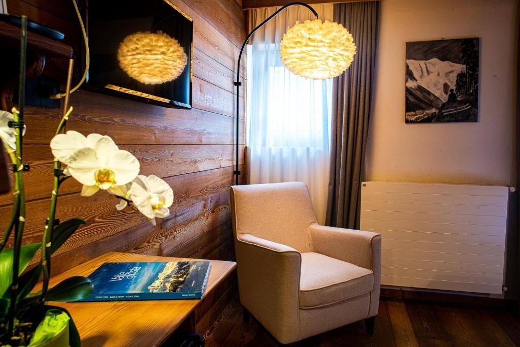 Een kamer met een houten wand, een witte radiator, een beige fauteuil en een boek op een tafel.