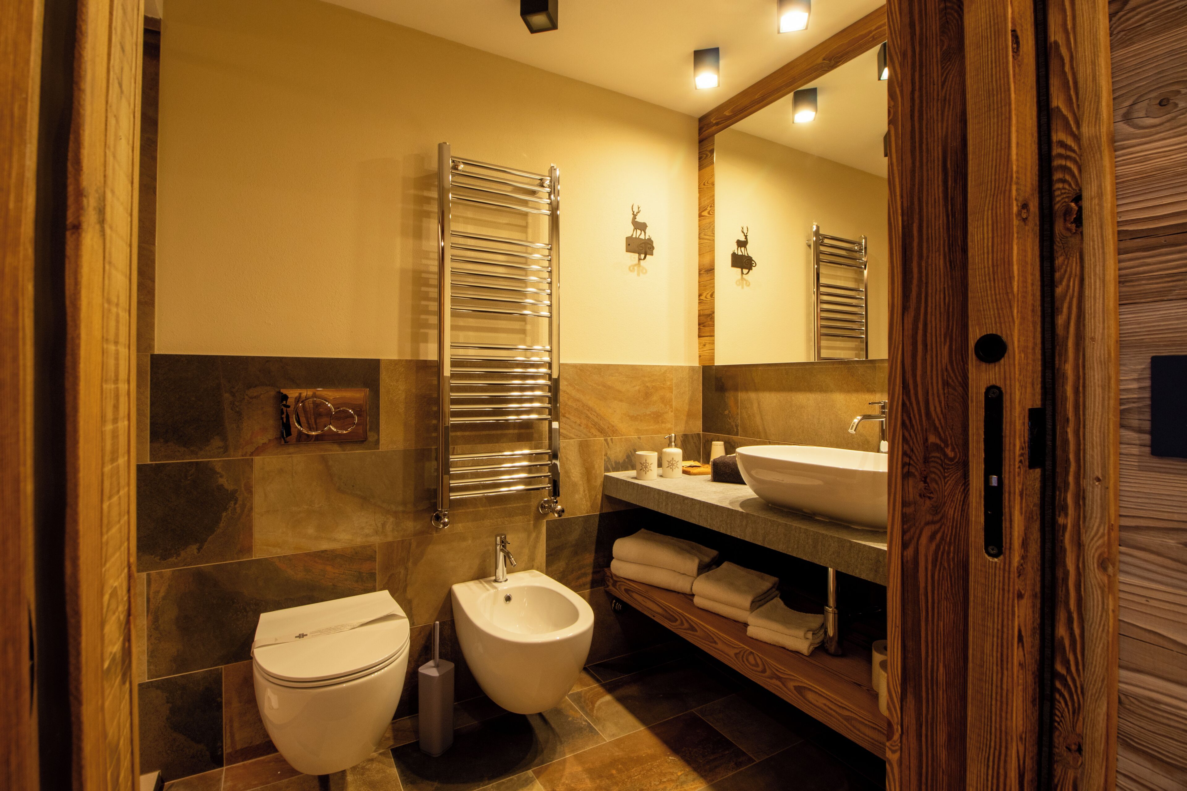 A modern bathroom with a bidet, a toilet, a sink, and a mirror.