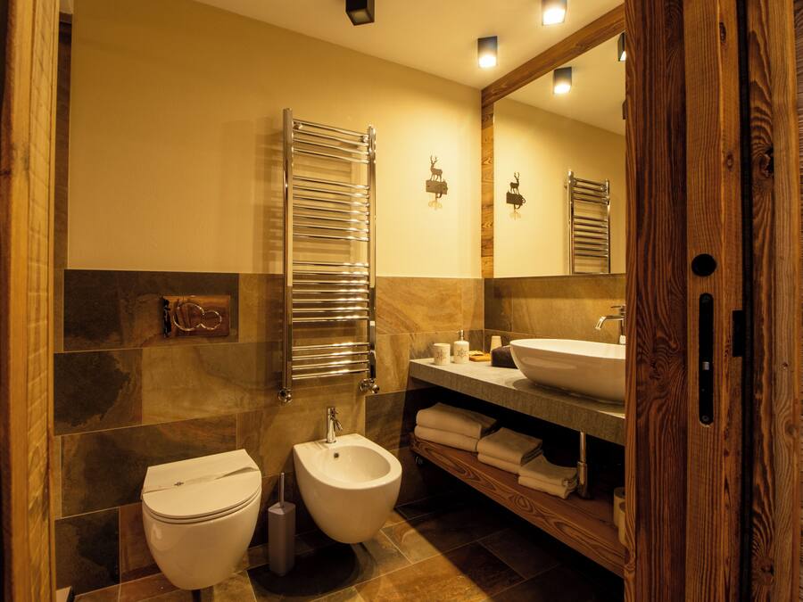 Een moderne badkamer met een toilet, een wastafel, een spiegel en een bidet.