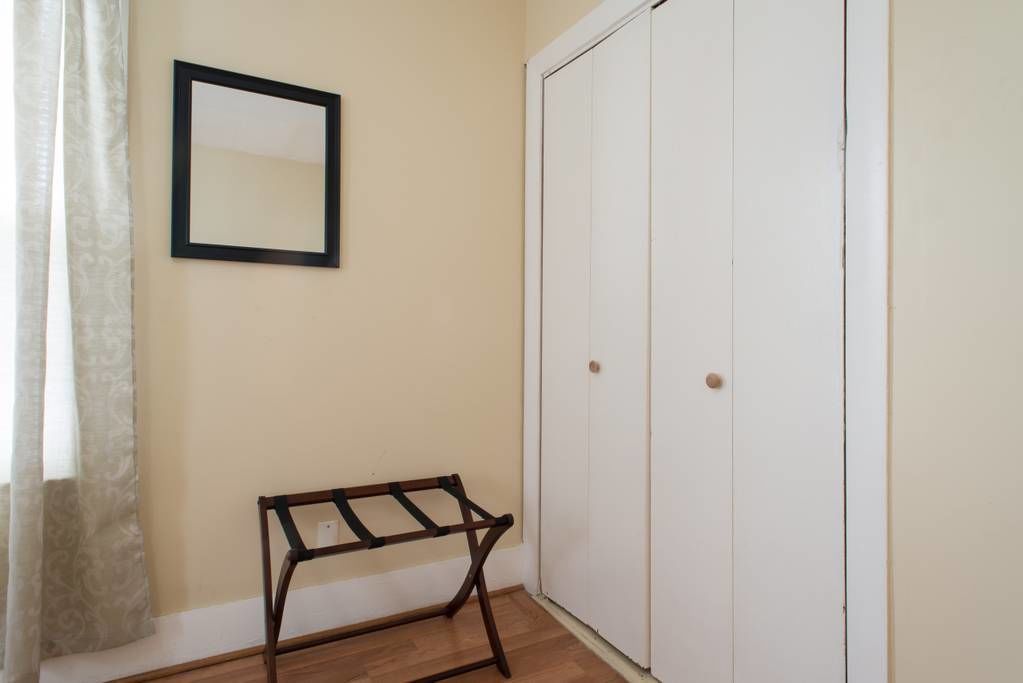 A room with a wooden bench, a white wardrobe, and a mirror on the wall.