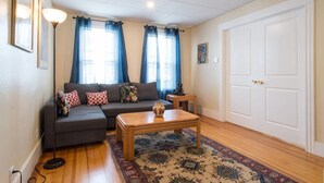 A living room with a sofa, a coffee table, a rug, and a door. - Apartments in Salem (Salem)