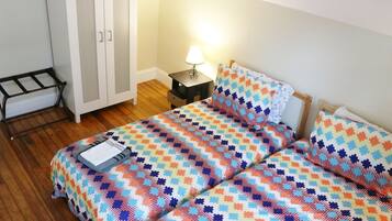 A bedroom with a bed, a nightstand, a lamp, and a wardrobe.
