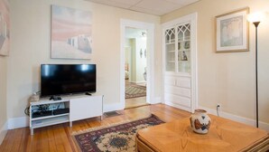 A living room with a flat-screen TV on a white stand, a wooden coffee table, a patterned rug, and a decorative vase. - Apartments in Salem (Salem)