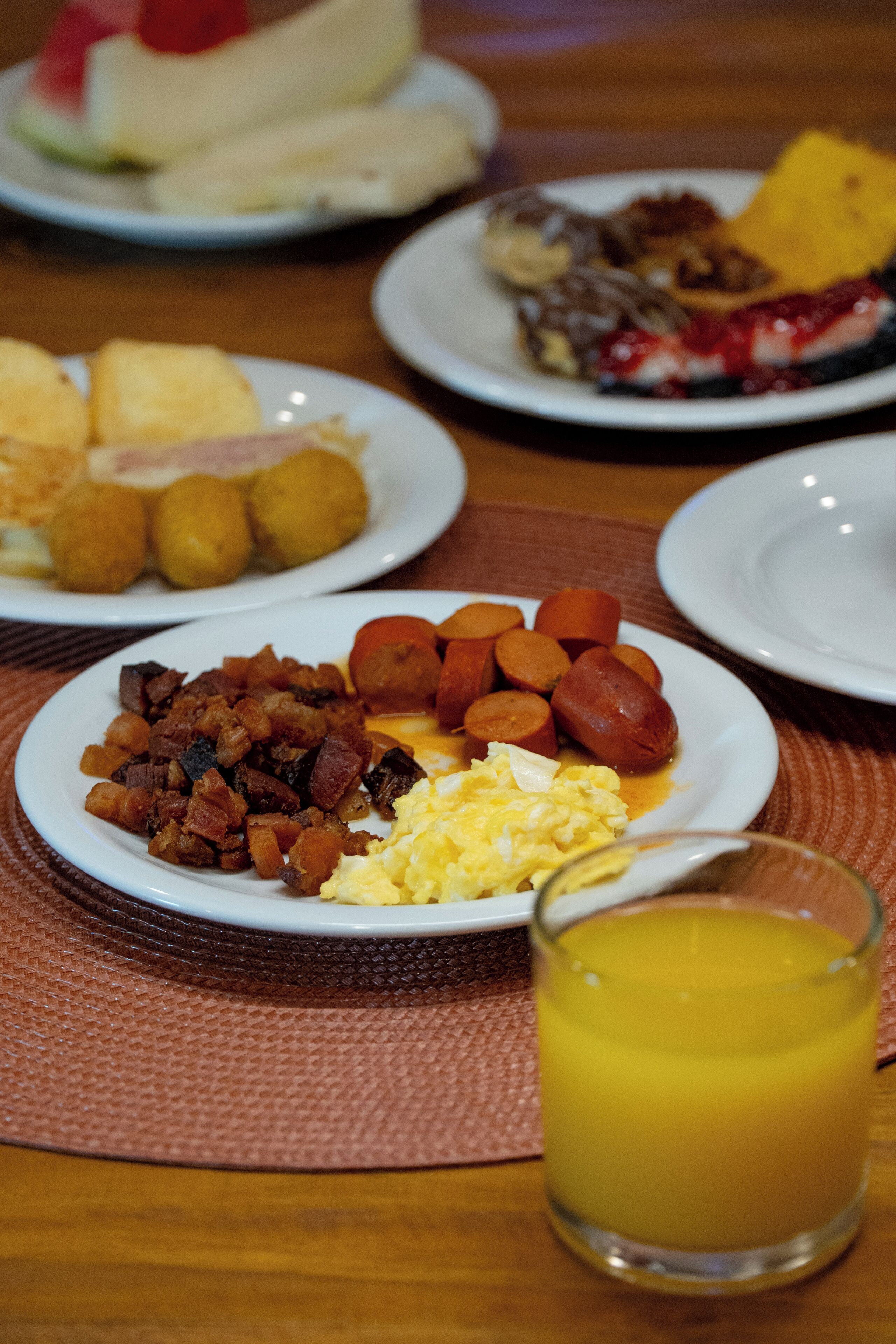 A breakfast table with plates of food including sausages, scrambled eggs, and toast.