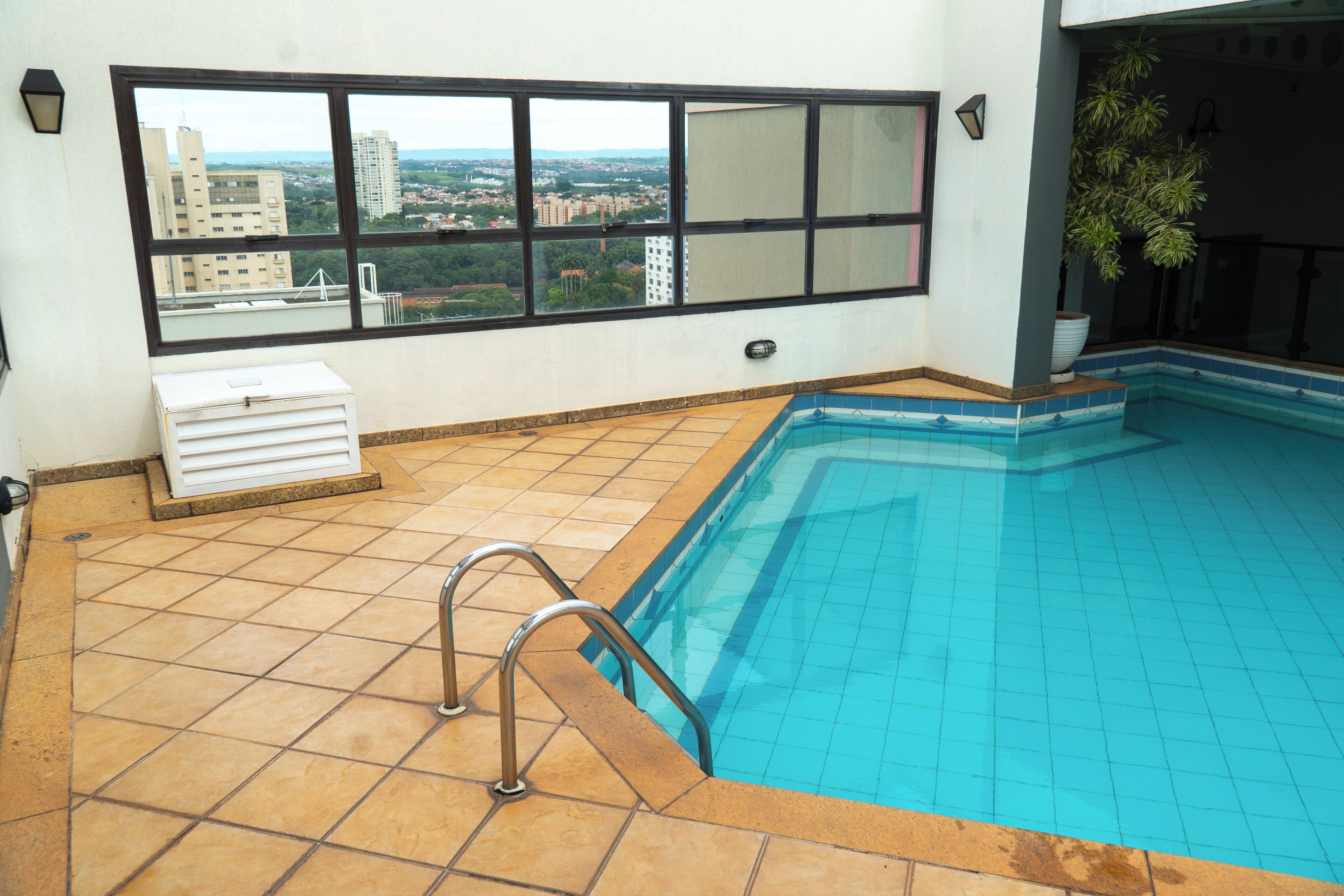 Una piscina con vista a un paisaje urbano a través de amplios ventanales.