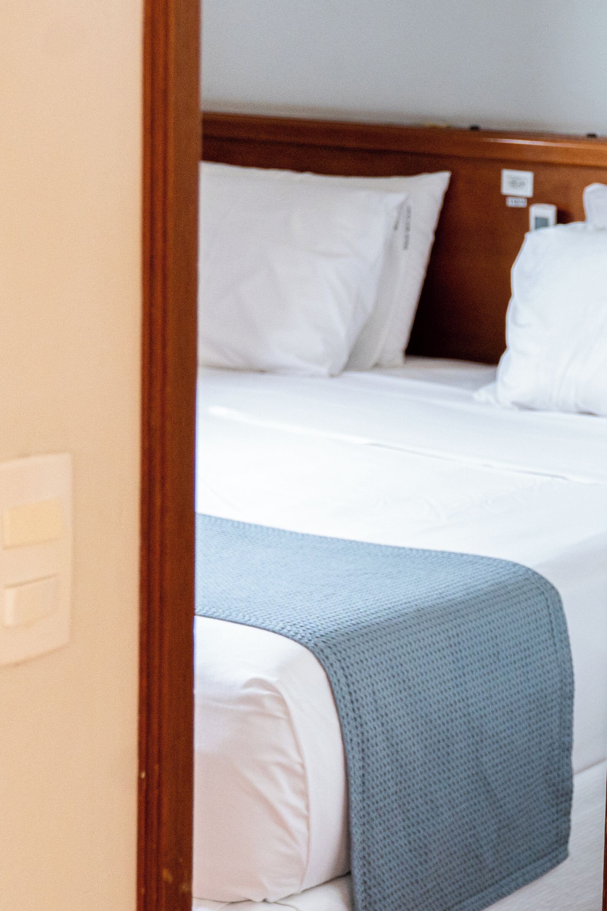 A hotel room with a bed, white bedding, and a wooden headboard.