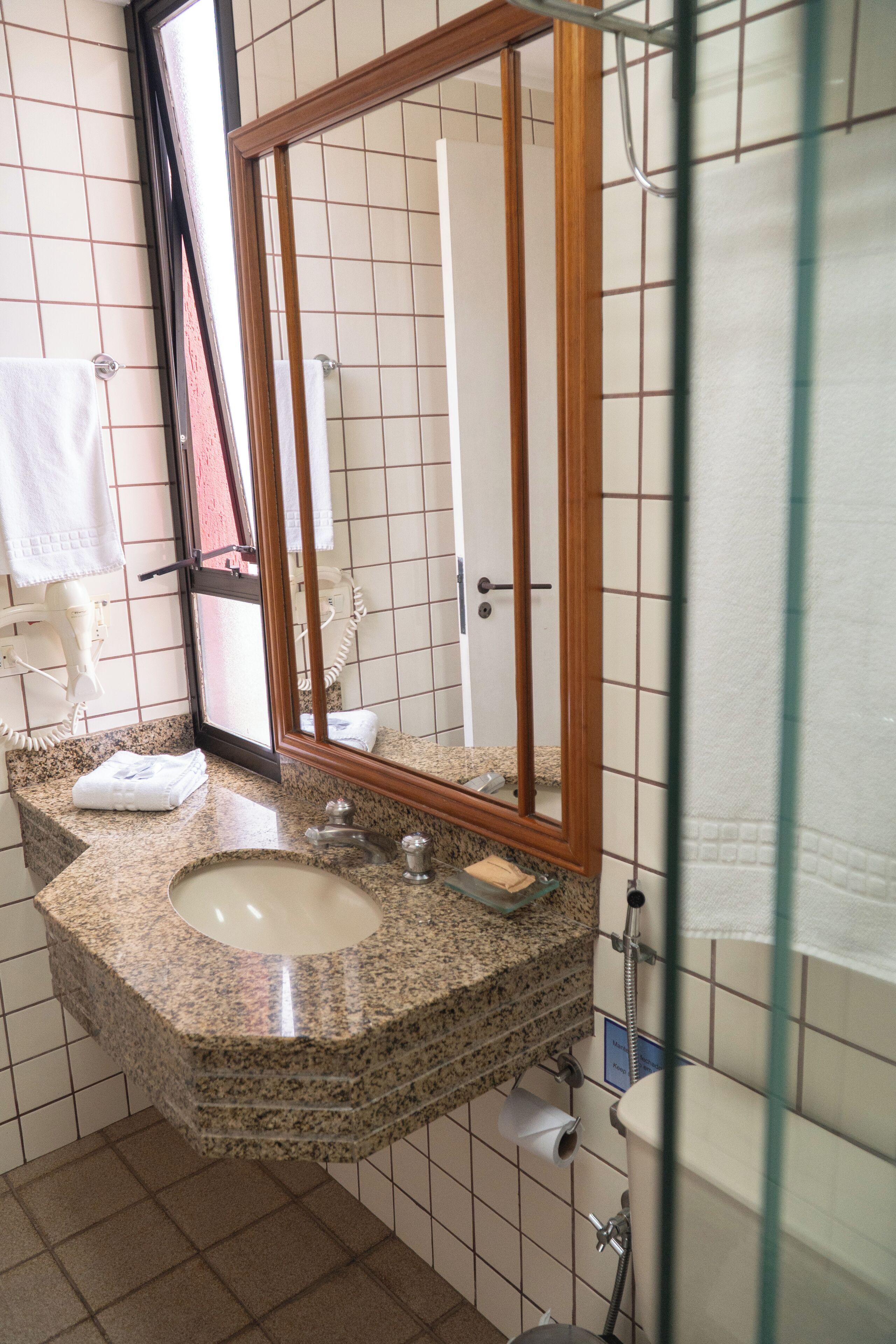 A bathroom with a granite countertop, a sink, a mirror, and a shower area.