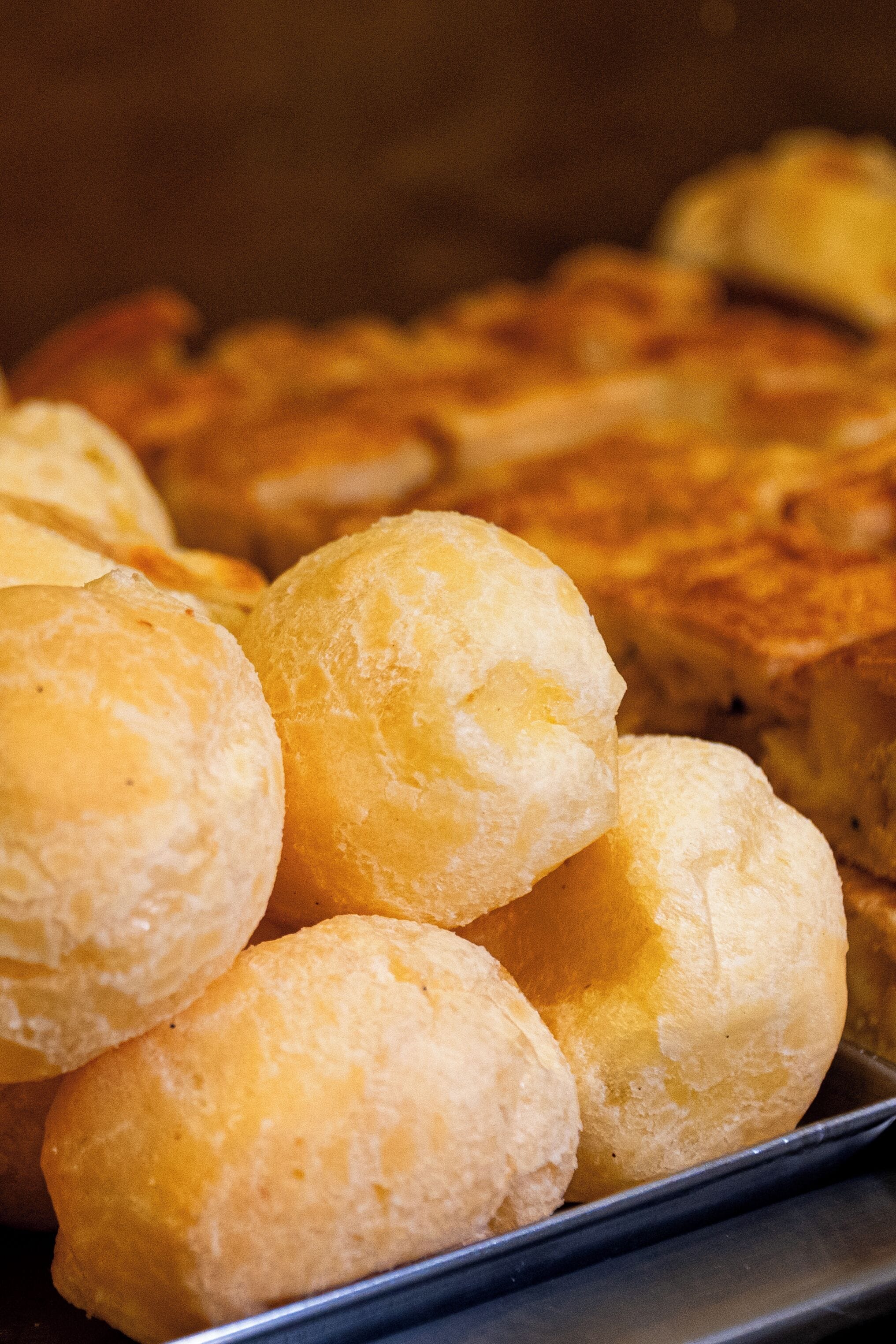 A tray of golden-brown pastries, likely cheese puffs, with a focus on their texture and arrangement.