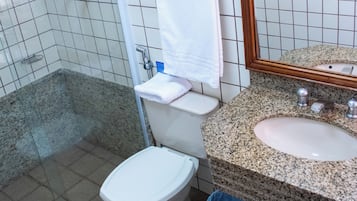 Un baño con ducha, inodoro, lavamanos y espejo.