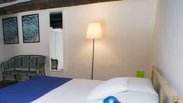 Ein Schlafzimmer mit Bett, Lampe, Stuhl und zwei Wandbildern.