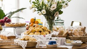 A buffet table with various food items, including pastries, bread, and fruits. - Home47 (Salerno)