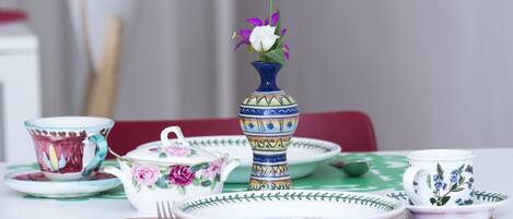 Una mesa dispuesta con varios platos, una tetera y un florero con flores.
