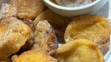 A tray of fried dough pastries with a dipping sauce.