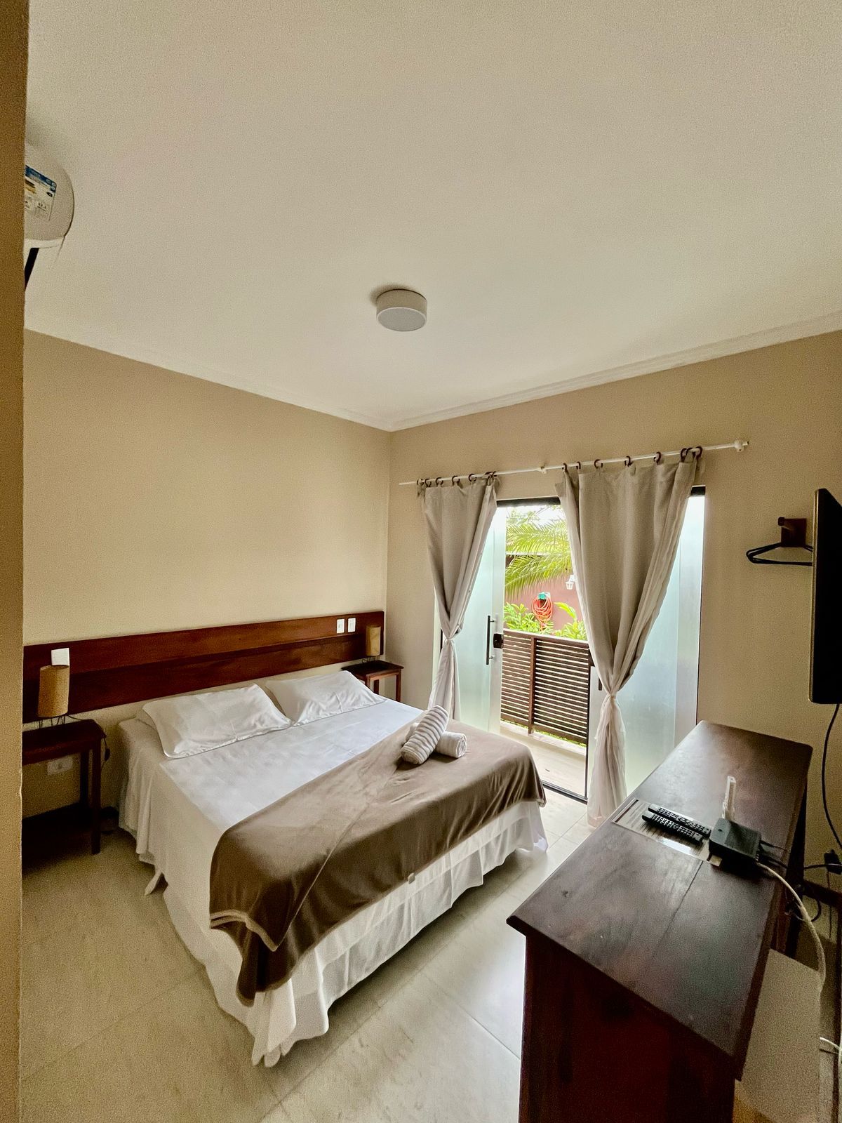 A hotel room with a bed, a desk, and a television.