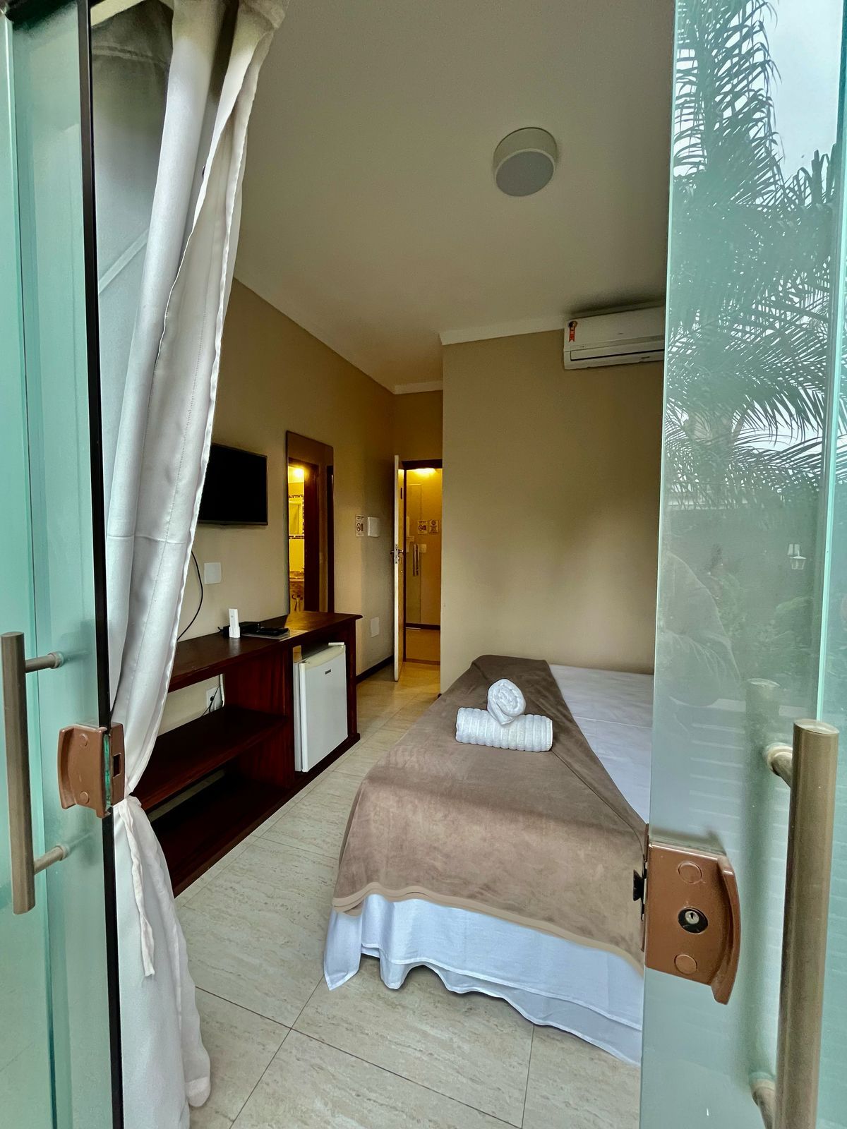 Una habitación de hotel con una cama, un escritorio, un espejo y un televisor.