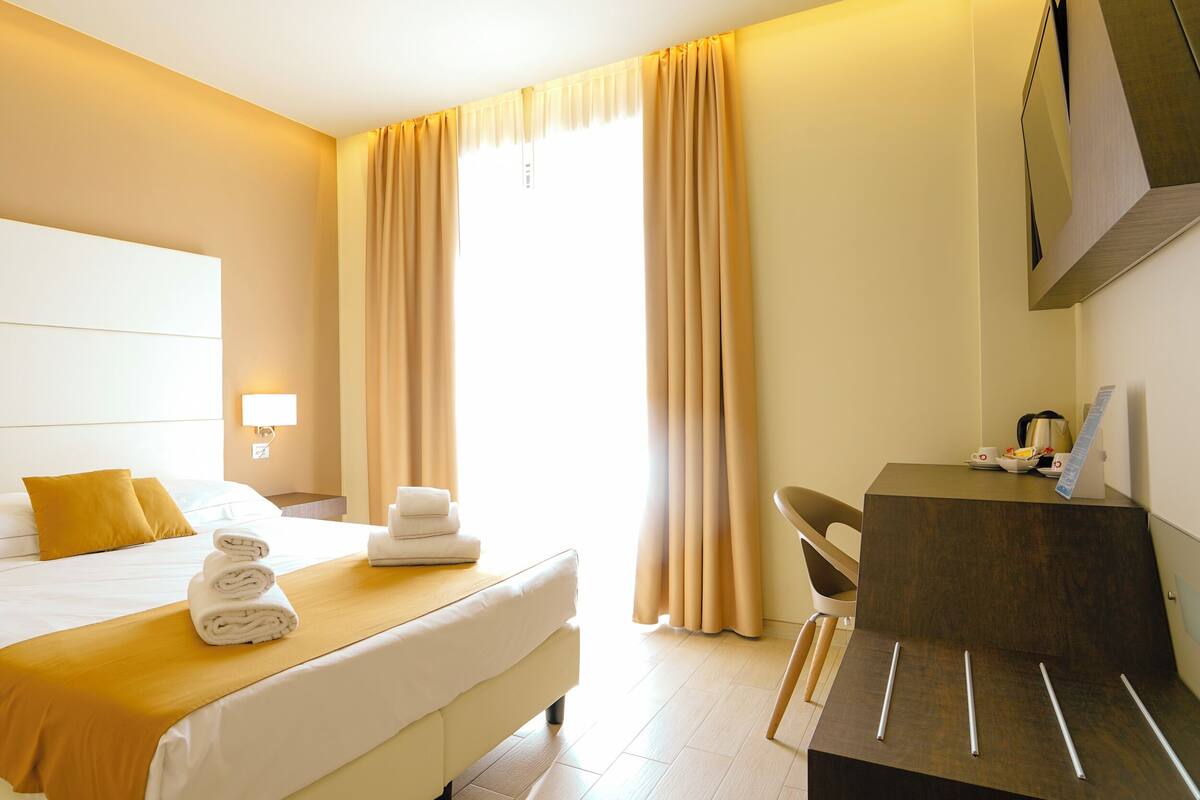 A hotel room with a bed, a desk, and a chair.