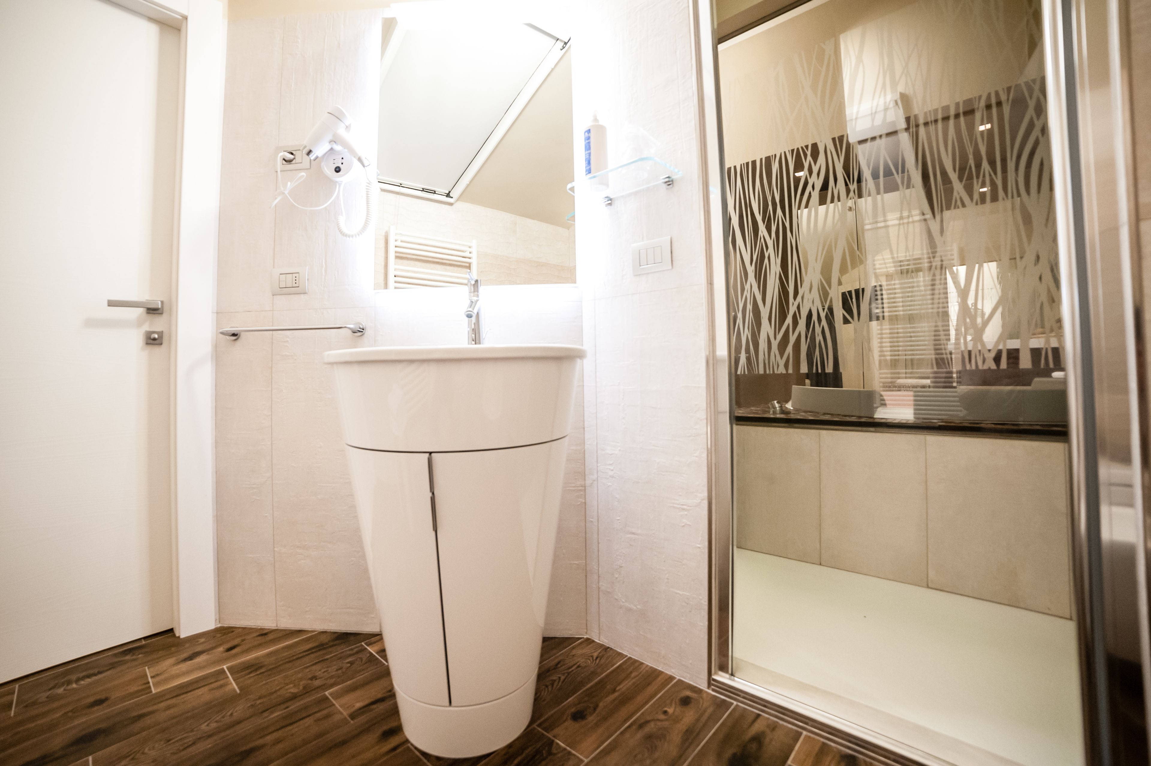 A modern bathroom with a white sink, a handheld showerhead, and a glass shower enclosure.
