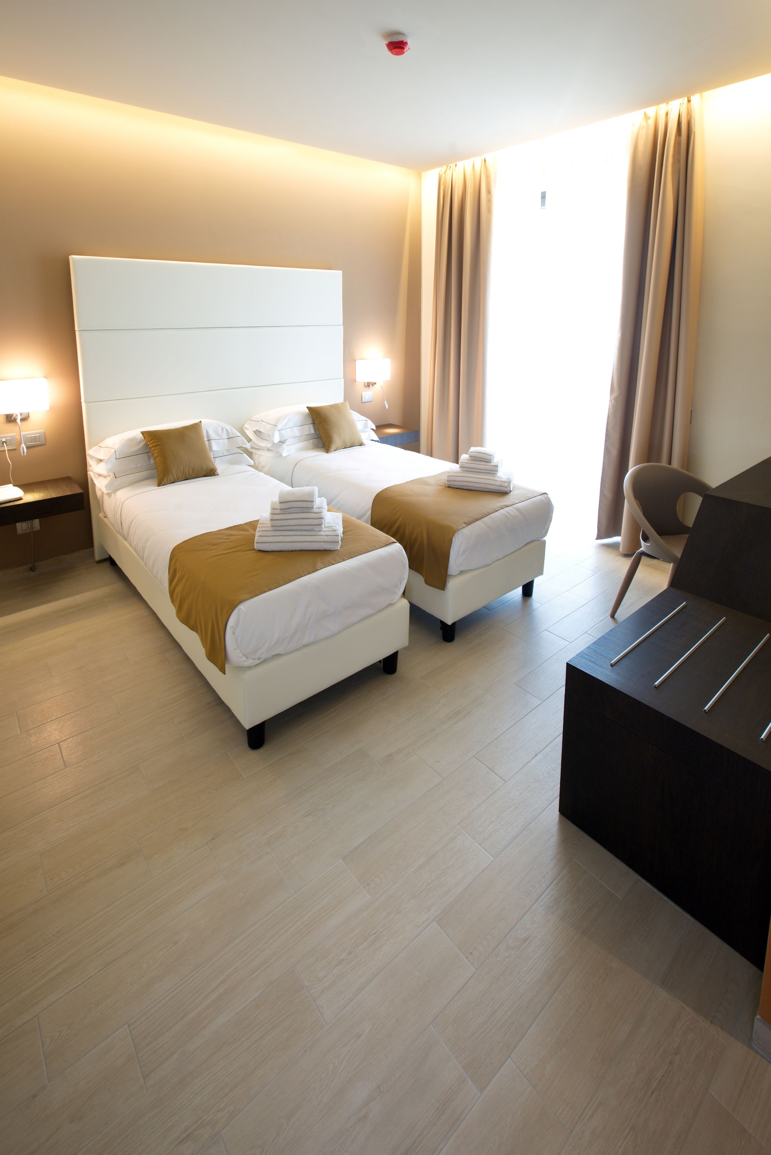 Een hotelkamer met twee bedden, een bureau en een stoel.