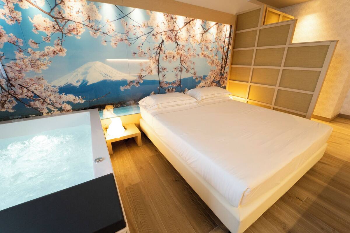 A modern bedroom with a large bed, a nightstand, and a wall-mounted TV.