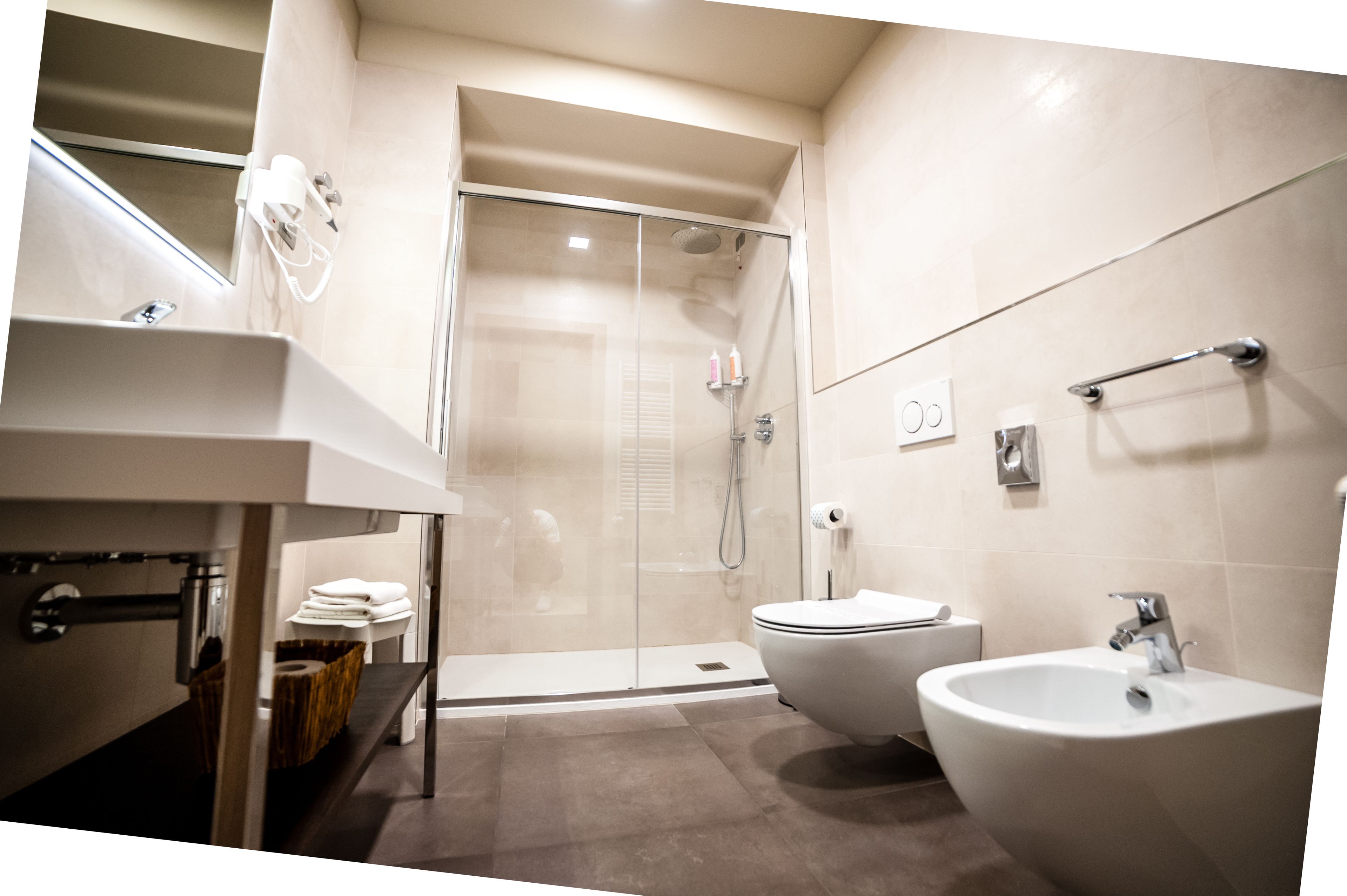 Un bagno moderno con doccia vetrata, lavandino, bidet e WC.