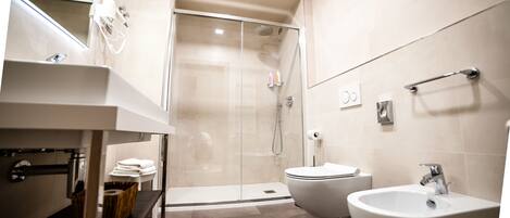 A modern bathroom with a glass-enclosed shower, a sink, a bidet, and a toilet.