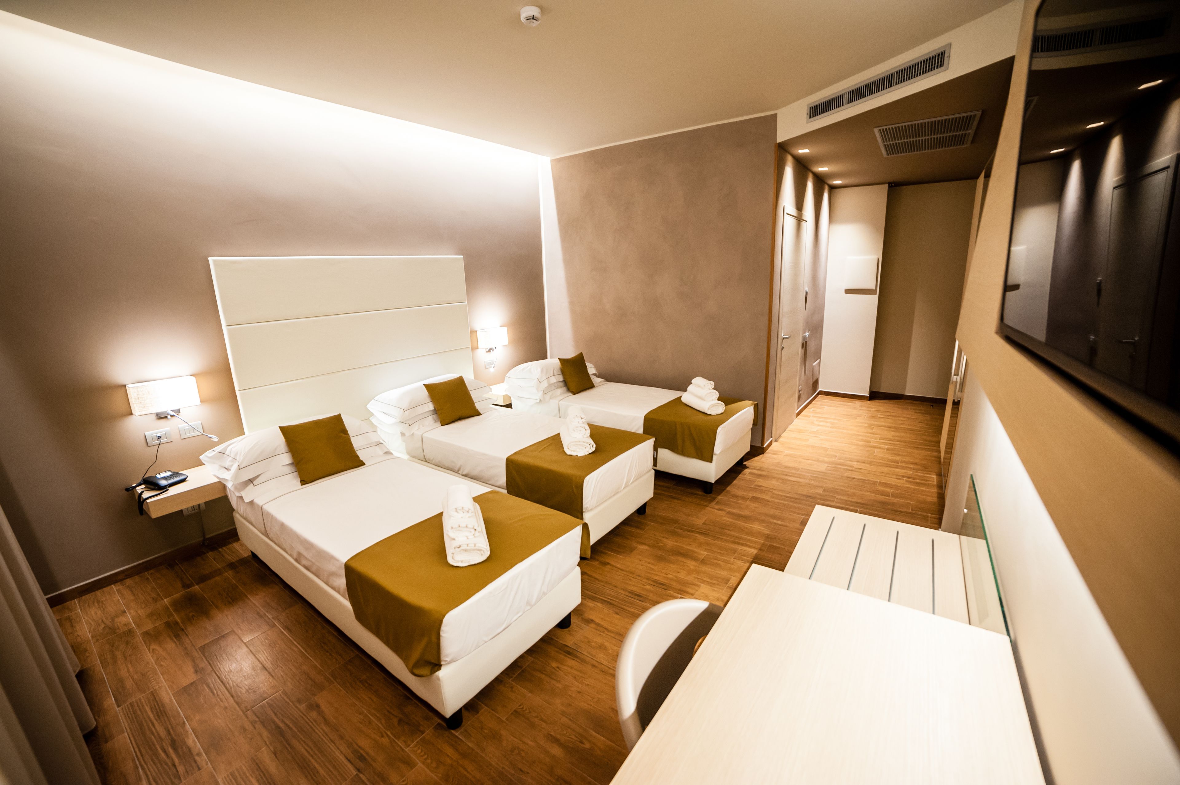 Quarto de hotel com duas camas, uma mesa e uma cadeira.