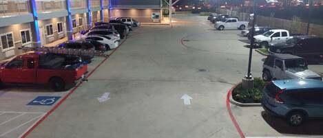 A parking lot with multiple cars, a handicap parking space, and a building with blue lighting.