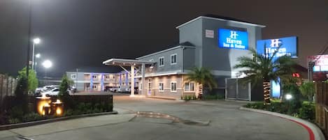 Un hotel con un letrero grande que indica Haven Inn & Suites, un estacionamiento y una entrada con acceso restringido.