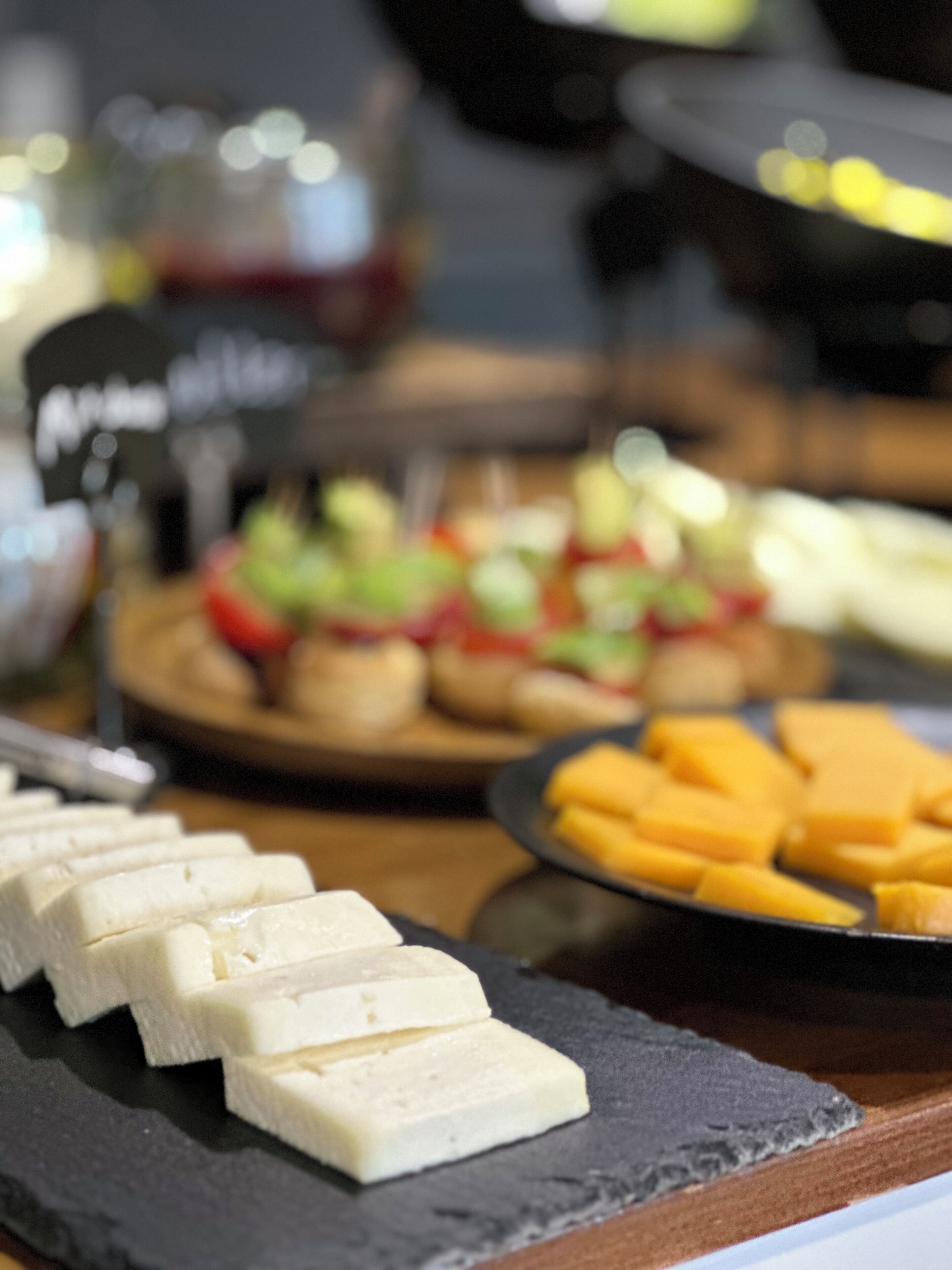 Un bufé con distintos alimentos, como queso, frutas y ensaladas.