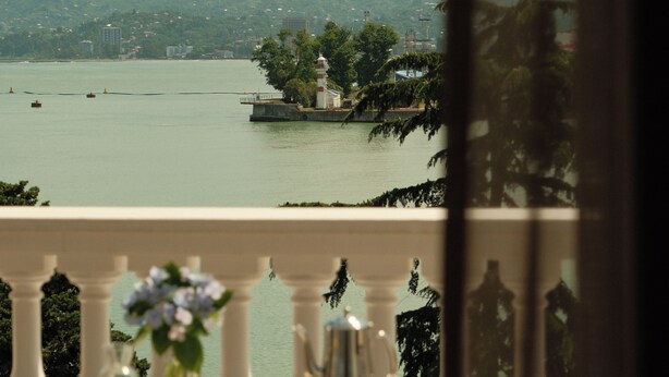 A dining table with breakfast items and a view of a lake and mountains. - Le Port Apart Hotel (Batumi)