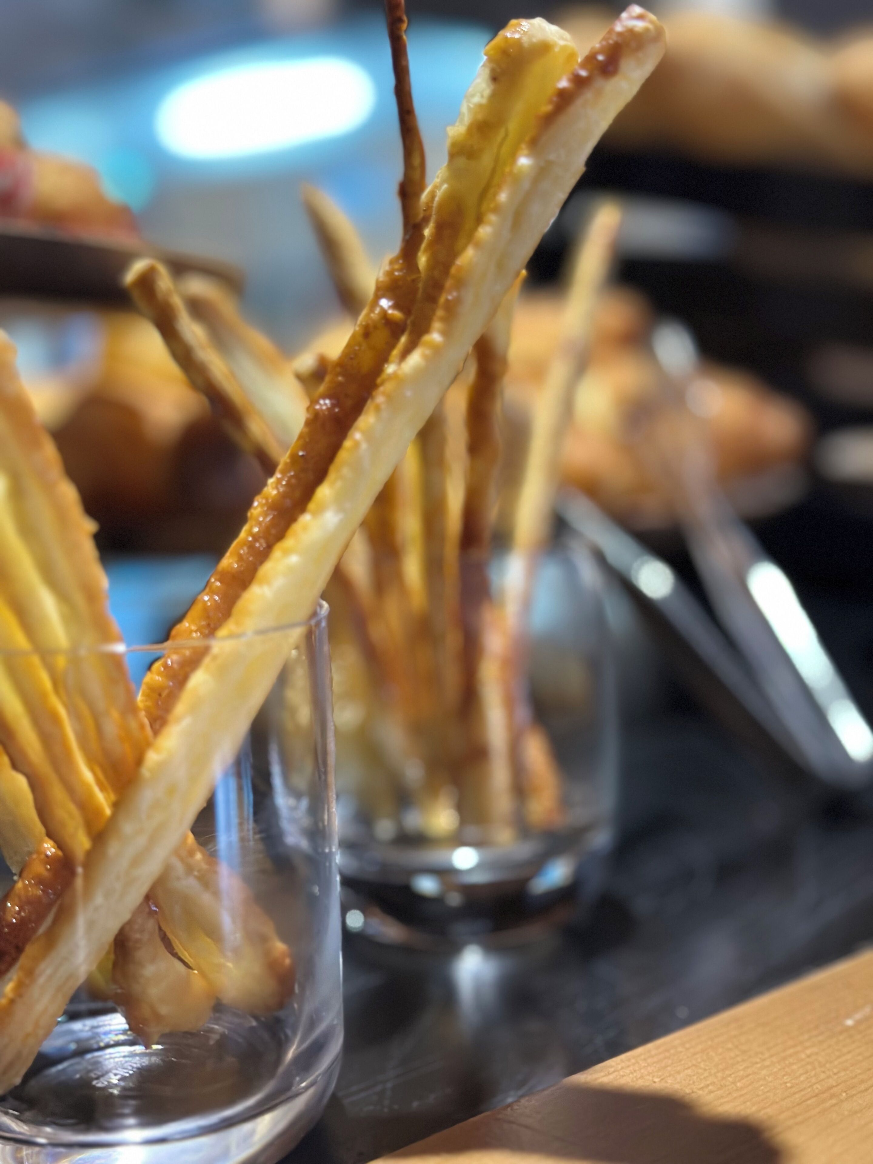 Et nærbillede af churros dyppet i chokolade, serveret i glas.