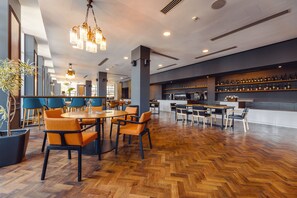 A spacious restaurant with wooden flooring, orange chairs, and a bar area with shelves of bottles. - Le Port Apart Hotel (Batumi)