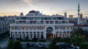A large, multi-story building with a prominent central entrance and arched windows. - Le Port Apart Hotel (Batumi)