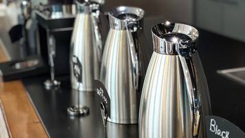 Een koffiehoek met verschillende roestvrijstalen koffiezetapparaten en een bordje met de tekst 'Black Tea'.