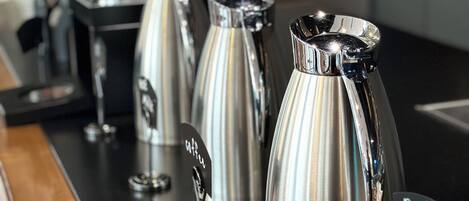 A coffee station with several stainless steel coffee makers and a sign labeled "Black Tea".