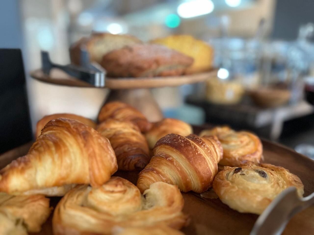 A display of assorted pastries, including croissants and other baked goods, arranged on a wooden board.