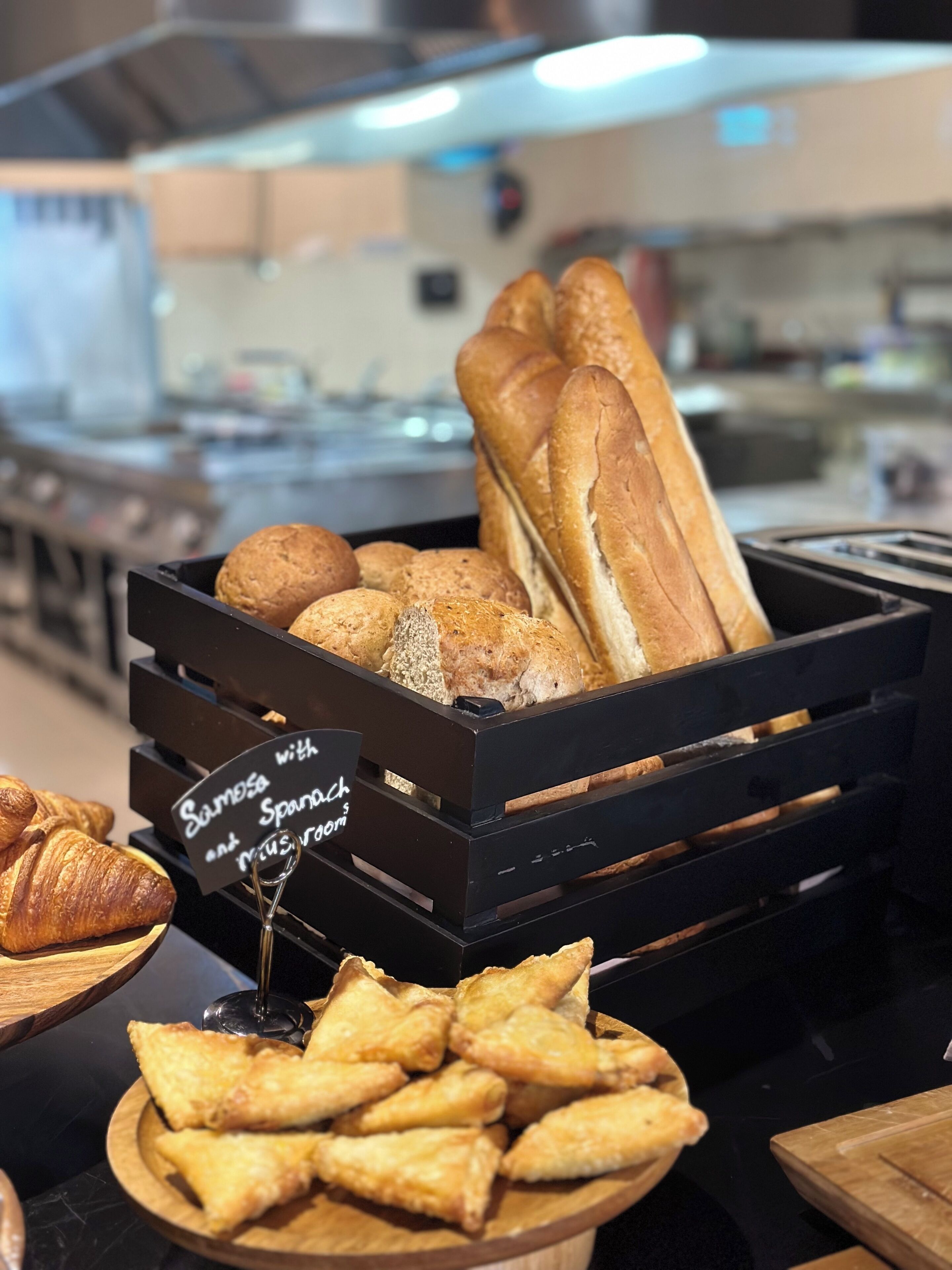 Présentation de divers produits de boulangerie, notamment du pain et des pâtisseries, dans un décor de boulangerie.