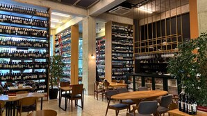 A wine cellar with shelves of wine bottles, wooden tables, and chairs. - Le Port Apart Hotel (Batumi)