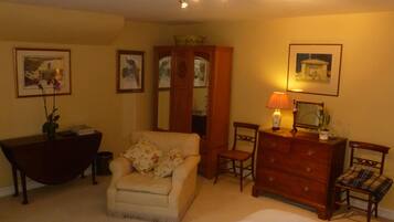 A bedroom with a bed, a chair, a dresser, a desk, and a mirror.