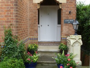 A brick building with a white door, a sign reading "LAUREL HOUSE 143", and a stone lantern. - Laurel House (Cheltenham)