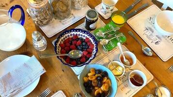 Una mesa de comedor de madera dispuesta con varios platos, incluyendo un bol de bayas, un plato de huevos y varios frascos pequeños.