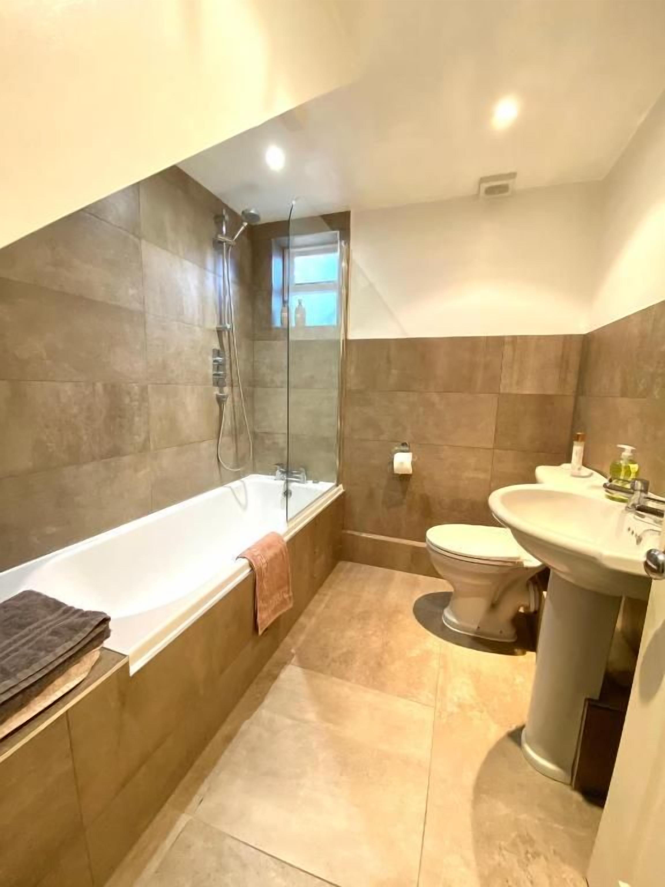 A modern bathroom with a bathtub, toilet, and sink.