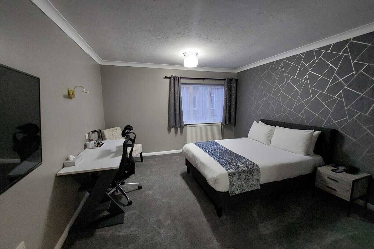 A modern hotel room with a bed, a desk, and a chair.