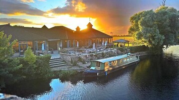 A riverside hotel with a boat dock, outdoor seating, and a sunset view.