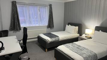 Habitación de hotel con dos camas, un escritorio y una silla.