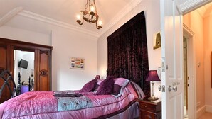 A bedroom with a large bed, a chandelier, a dark curtain, and a door labeled "Guest Room". - Heritage Bed & Breakfast (Calne)