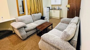 A living room with a sofa set, a coffee table, a kitchen area, and a mirror. - Trivelles Seaforth (Liverpool)